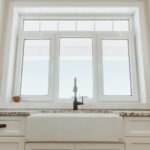 White framed three part kitchen window with the left and right outer window operable for tilt and turn and a horizontal window on top.